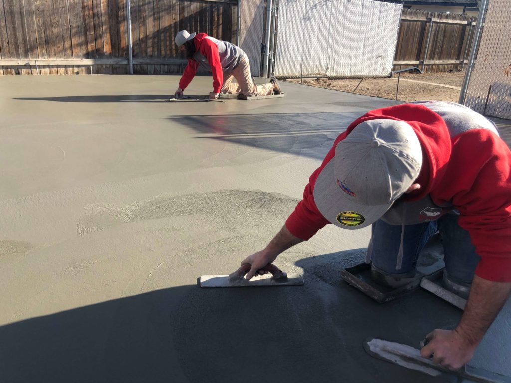 Men Using Knee Boards To Finish Concrete